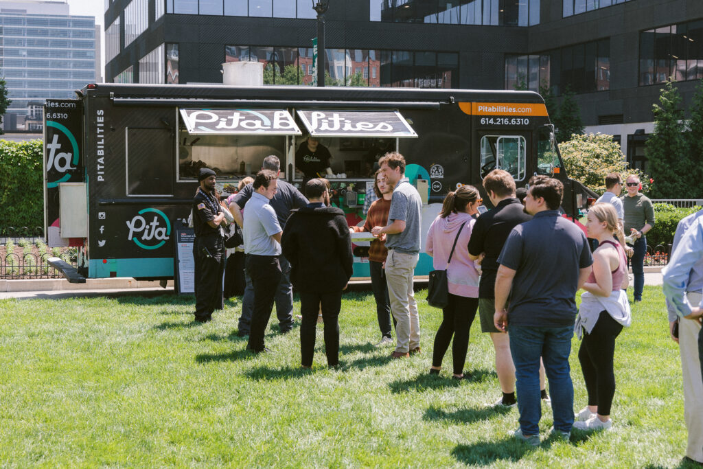 people standing in line at a food truck outside