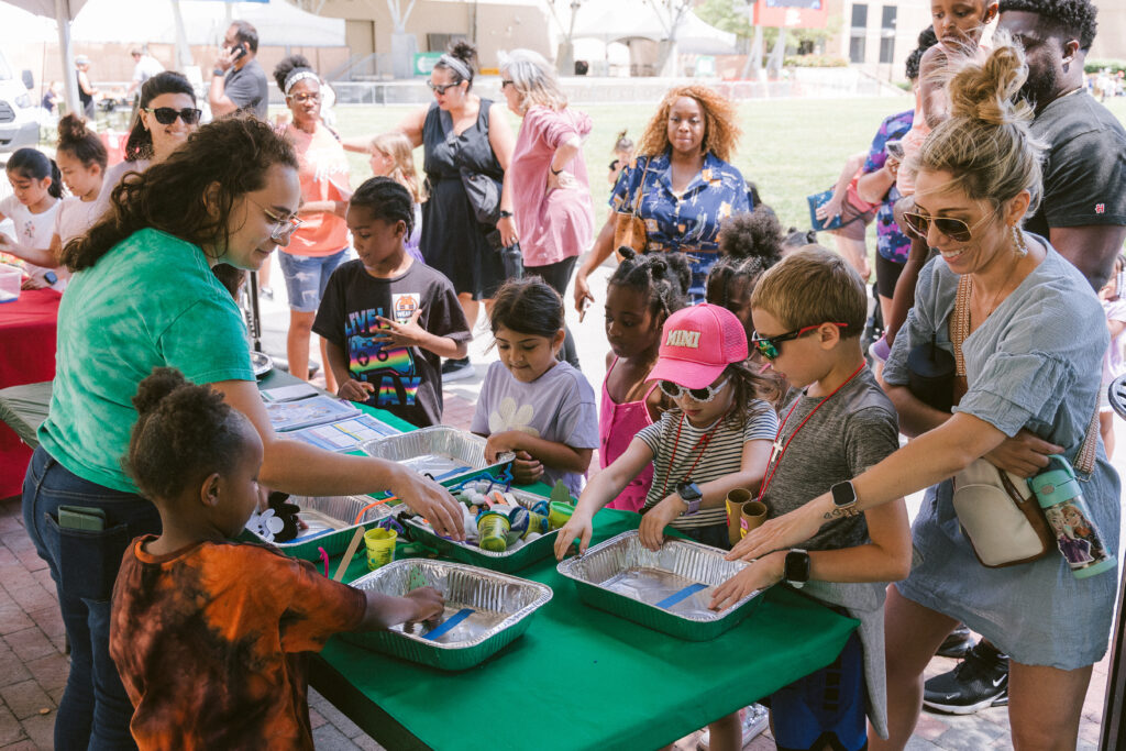 woman helping kids with a fun project outdoors