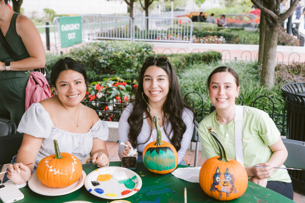 three women decorating pumpkins